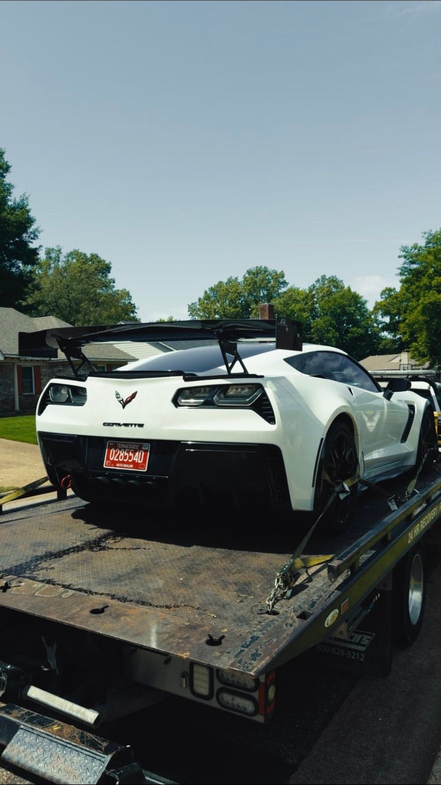 Smiths Towing flatbed hauling a white sports car on a residential street near Lakeland, TN